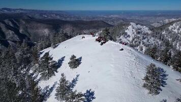 Aerial drone view of mountaineers in the summit. Mountain surrounded by frozen trees. Winter landscape. video