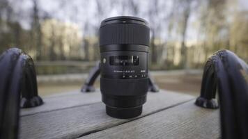 RUSSIA, MOSCOW-DECEMBER, 2020. Close-up of professional camera lens. Action. Lens for professional camera lies on bench in park. Lost expensive camera lens in park photo