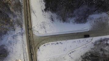 T-shape crossroad in snowbound forest at winter day. Aerial view. Footage. Car rides by crossroad in snow-covered forest at winter day. Aerial view. photo