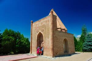 The Aisha-Bibi, a mausoleum-museum, displays an emblematic dome and elaborate terracotta artistry, echoing the grandeur of 12th-century Karakhanid architecture against Central Asia's broad heavens. photo