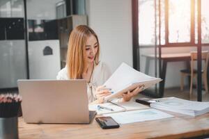 Young busy business woman manager, lawyer or company employee holding accounting bookkeeping documents checking financial data or marketing report working in office with laptop. photo