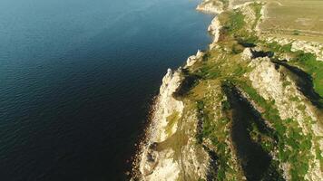 aereo Visualizza di pittoresco lungo bianca scogliera coperto con verde erba, alberi e arbusti vicino il mare a caldo estate giorno. sparo. bellissimo paesaggio di scogliera e riva del mare video