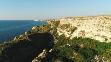 Aerial view of beautiful white cliff range and stones with green grass, trees and shrubs near the clean blue water at warm summer day. Shot. Beautiful landscape of coastline and seashore video