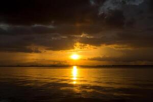 puesta de sol a el lago con oscuro nube. foto