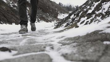 Close-up of male legs in winter shoes walking on snow. Footage, View of walking on snow with Snow shoes and Shoe spikes in winter. Men's legs in boots close up the snow-covered path photo