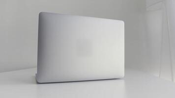 Rear view of a white laptop isolated on white background. Action. Modern slim design of a new laptop made of aluminum material on white table, concept of modern technologies. photo