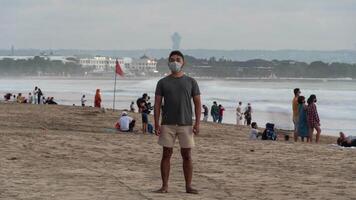 uomo in piedi con maschera su il spiaggia durante covid-19 coronavirus pandemia tempo periodo video