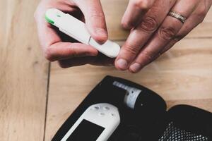 Woman pricking her finger to check blood glucose level with glucometer, test blood glucose for diabetes photo