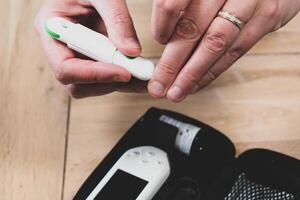 Woman pricking her finger to check blood glucose level with glucometer, test blood glucose for diabetes photo