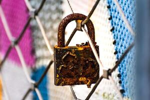 Rusty padlocks attached to the metal railing of a bridge, tradition of padlocks, symbol of eternal love photo