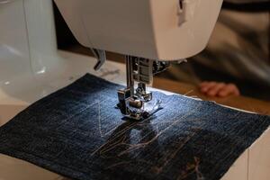 Man using a sewing machine with a blue garment, for repair work, customization, creation, upcycling photo