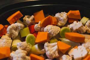 Raw vegetables cut into small pieces prepared for steaming, cauliflower, butternut, leek, carrot photo