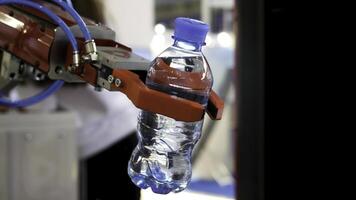 Close up for the red robot hand holding a bottle of wate on blurred background, artificial intelligence concept. Media. Automatic industrial machinery equipment. photo