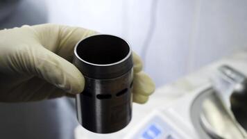 Close up of hands in medical gloves putting chemical powder from chemical scoop to small metal container at laboratory. Hands putting white reagent into chemical receptacle, science conceept. photo