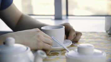 cerca arriba mans manos con taza de café en el mesa y ventana antecedentes. empresario café descanso de cerca, manos con americano taza en madera mesa, cerca arriba foto