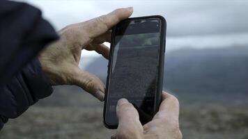 Close-up of man photographing mountain landscape with man. Clip. Phone screen is in hands of man photo