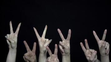 Crowd hands with sign of victory. Close-up of many hands with fists raised up then changed to sign of victory. Metaphor of war and peace photo