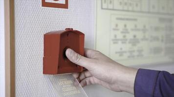 The hand of man is pushing fire alarm on the wall. Clip. Hand of man pushing fire alarm switch on the white wall as background for emergency case at the new factory building photo