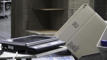 Close-up view of the hands of a manufacturing worker putting packed products in cardboard boxes, before export or shipping during manual work in a cosmetics factory. Clip. Worker in warehouse photo