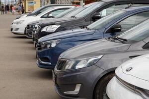 Row of cars on summer day parking - close-up view on noses from side photo