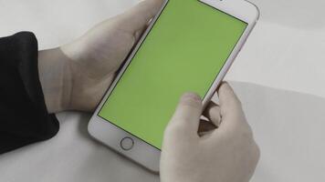 Hand holding touch green screen smart phone on white background. Stock footage. Hand tapping on a cell phone with chroma key. photo