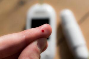 mujer punción su dedo a cheque sangre glucosa nivel con glucómetro, prueba sangre glucosa para diabetes foto