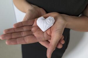 Woman holding white 3d printed heart. Ideal for diverse concept, love and health, gratitude and charity either technology photo