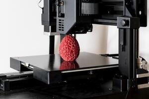 Close up of a 3d printer printing a red polygonal egg photo