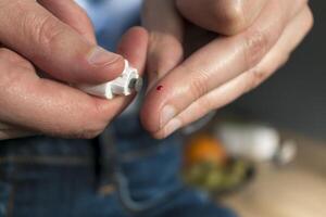 Woman pricking her finger to check blood glucose level with glucometer, test blood glucose for diabetes photo