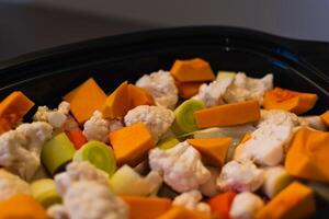 Raw vegetables cut into small pieces prepared for steaming, cauliflower, butternut, leek, carrot photo