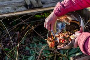 Person who put in a composter some kitchen waste like vegetables, fruits, eggshell, coffee grounds in order to sort and make bio fertilizer photo