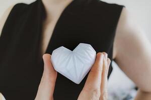 Woman holding white 3d printed heart. Ideal for diverse concept, love and health, gratitude and charity either technology photo