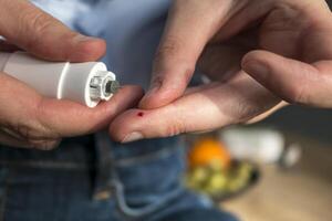 Woman pricking her finger to check blood glucose level with glucometer, test blood glucose for diabetes photo