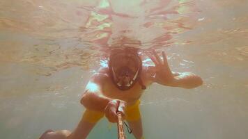 Underwater Snorkeling Adventure. A snorkeler explores beneath the surface, greeting with a peace sign. video