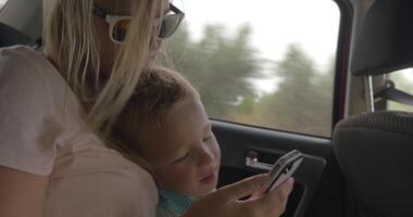 Mother and child video chatting on mobile in car