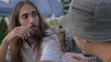 Men friends talking and smoking in outdoor cafe video