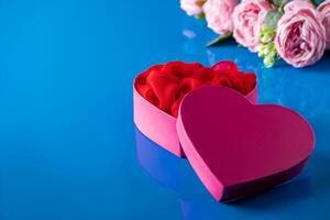 Heart shaped open gift box on blue background. photo