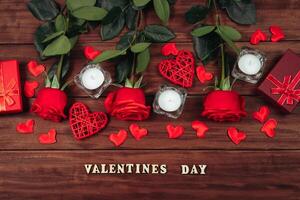 rojo rosas y velas en un oscuro de madera antecedentes. San Valentín día, sitio para texto. foto