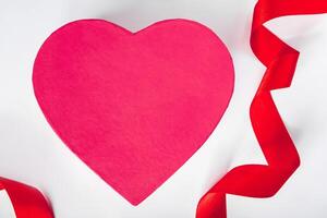 concepto de día de san valentín. cinta de seda roja y corazón sobre un fondo blanco. foto