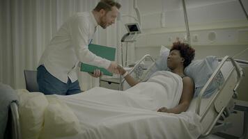 jung afrikanisch Frau mit lockig Haar Lügen im Klinik Bett reden zu Arzt video