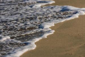 blanco espuma desde el olas a el arenoso playa en el Mañana en Egipto detalle foto