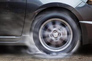 Car racing spinning wheel burns rubber on floor. photo