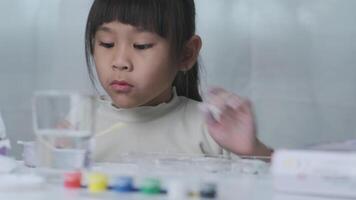 linda pequeño niña haciendo bricolaje yeso y pintura a hogar. niños pintar en yeso esculturas con familia en día festivo. imaginación y creatividad actividades. video