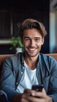 ai generativo hermoso joven hombre tomando un selfie a hogar utilizando inteligente teléfono dispositivo contento chico sonriente en el cámara interior foto