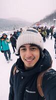 AI Generative Young man wearing winter clothes taking selfie picture in winter snow mountain  Happy guy with backpack hiking outside  Recreation sport and people concept photo