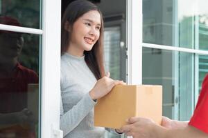 Happy smiling woman receives boxes parcel from courier in front house. Delivery man send deliver express. online shopping, paper containers, takeaway, postman, delivery service, packages photo