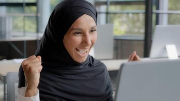 Young excited arab woman checking email on laptop concentration reading gets good news amazed happy businesswoman winner celebrating victory rejoices in success feels joy receives reward career growth photo