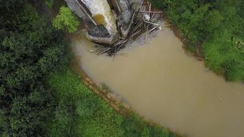 Top view of dam on dirty river. Clip. Industrial dam on dirty river. Dam or dam in bed of brown river with green forest photo