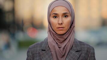 Close up portrait sad upset female face pensive serious muslim business woman young islamic girl ethnic lady wearing hijab stands in city looks away looking at camera religious discrimination concept photo