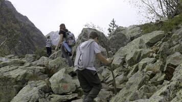 Family hike on rocks on background of autumn trees. Creative. Mother and her sons are walking on rocks in hike in mountain forest. Family hike through dangerous stone places photo